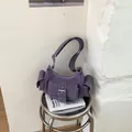 Detailed shot of purple suede underarm bag with multi-pocket design on white book - No Pendant / Purple