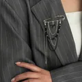 Detail of silver safety pin brooch with black heart pendant and layered chains on suit - Silver and Black-00386