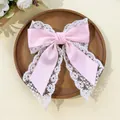 Detail of pink satin bow hair clip with delicate white flower lace trim on wooden tray - Light Pink