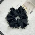Detailed view of black satin scrunchie with grey beaded edges on a white tray - Satin Large Black