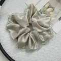 Close-up of champagne satin scrunchie featuring luxury crystal beads on white tray - Satin Large Cream