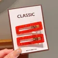 Set of two rectangular red resin hair clips with golden mica texture on display card - Square Red Floral Hair Clips