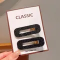 Two black glitter oval cutout hair clips displayed on a white product card - Square Fine Glitter Black Hair Clips