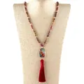 Détail d'un collier bohème avec pierres facettées et long pompon en soie rouge - 86cm / Rouge