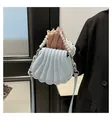 Borsa a mano azzurra a forma di conchiglia con manico di perle portata da una modella - Blu