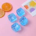 Pack of four blue translucent ice cube squishy toys with snowflake inserts on pink background - Blue Snowflake Square Style