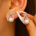 Primo piano di orecchini a perno incrociati con perle e cristalli sull'orecchio - Stile Incrociato con Perla e Strass / Argento (9661)