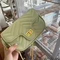 Dettaglio della borsa a tracolla trapuntata verde chiaro con fibbia dorata e cuciture a V - verde fresco