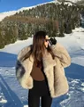 Nahaufnahme eines flauschigen beigen Pelzmantels mit großem Revers vor winterlichen Bergen - S / Khaki