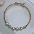 Detailed view of an adjustable 14K gold plated wire wrapped bracelet with freshwater pearls - Gold Eight Near Round Pearl Style
