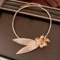 Dettaglio macro di collana a girocollo floreale in oro su vassoio di pelle marrone - Collana - Oro