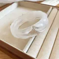 Detail shot of a translucent white marbled acrylic bangle with wavy edges in a jewelry box - White