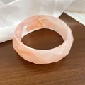 Vista macro dettagliata della trama liscia e del bordo ondulato di questo bracciale rosa - Rosa