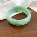 Dettaglio di bracciale rigido in resina verde chiaro marmorizzata con bordo ondulato - verde scuro
