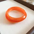 Detail view of glossy orange acrylic bangle with irregular marble swirl design - Orange