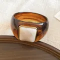 Primer plano de un brazalete de acrílico ámbar con incrustación cuadrada de mármol - Café-Marfil