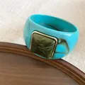 Detalle de brazalete de acrílico azul con elemento cuadrado jaspeado y borde dorado - Cian-Verde