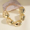 Close-up view of golden irregular pleated metal pendants on a chic statement necklace. - Necklace / Gold