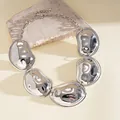 Detail view of a chunky silver pleated metal statement necklace on a stone prop - Necklace / Silver