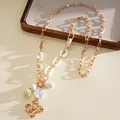 Close-up of elegant gold chain necklace with white acrylic links and flower pendant - Gold-White