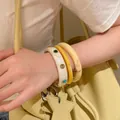 Dettaglio di tre bracciali rigidi in resina a strati con pietre colorate sul polso - Stile Marmo Giallo Bianco / Set di 3 / Bianco Ambra