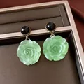 Detailansicht der Vintage-Ohrringe mit grüner Harzrose in einem braunen Schmucktablett - Vintage Rosenanhänger (20#) / Schwarz-Hellgrün
