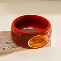 Macro detail of acrylic bangle featuring amber cabochon inlay and elegant gold trim - Irregular Geometric Style / Orange And Light Yellow