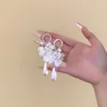 Dettaglio di eleganti orecchini a petalo bianco con perle e pendenti a goccia perla - Stile Pendente Perla Fiore di Conchiglia / Argento