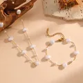 Detail shot of golden shell and pearl necklace bracelet set on a textured background - White Shell Necklace and Bracelet Set (C713-K707)