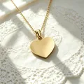 Gedetailleerde macro-opname van een gepolijste gouden hart hanger aan een ketting - Ketting met hartjeshanger / Goud