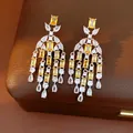 Nahaufnahme von Vintage-Quastenohrringen mit gelben und klaren Zirkon-Tropfen auf Lederbox - Weizenquasten-Stil / Silber-Gelb