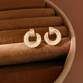 Close-up detail of 18k gold plated round stud earrings with sparkling cubic zirconia - Gold