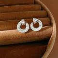 Macro view of circular zirconia stud earrings in a brown velvet jewelry display box - Silver