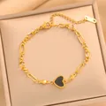 Makro-Detailaufnahme eines raffinierten goldenen Edelstahl-Herzarmbands auf Seidenbox - Europäische Büroklammer-Kette (728) / Schwarze Muschel Herz