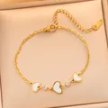 Gros plan détaillé d'un bracelet en acier doré avec cœurs blancs et petits cristaux - Chaîne de Cœur de Luxe (725) / Cœur de Coquille Blanche Dorée (725)