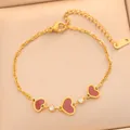 Gros plan d'un bracelet en acier doré avec des breloques cœur rouges et strass. - Chaîne de Cœur de Luxe (725) / Cœur de Coquille Rouge Dorée (725)