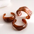 Detailed macro shot of three amber-toned acrylic cuff bracelets featuring marble swirl textures - Three-Piece Set / Brown