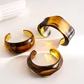 Detailed macro view of three chunky amber acrylic bangles with marbled geometric pattern - Three-Piece Set / Light Coffee