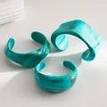 Detailed view of three turquoise marbled acrylic bangles with irregular geometric shapes. - Three-Piece Set / Cyan