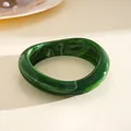 Primer plano de un brazalete de acrílico jaspeado verde oscuro con forma irregular - Estilo Geométrico Textura de Mármol / Verde oscuro