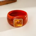 Macro shot of a vintage acrylic square bangle with an amber-colored inlay. - Irregular Geometric Style / Orange And Coffee