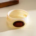 Detailed view of a vintage cream marble acrylic bangle with amber resin oval stone - Irregular Geometric Style / Beige White And Dark Brown