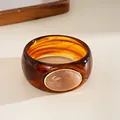 Macro detail of a vintage tortoiseshell acrylic bangle with an oval stone inlay. - Irregular Geometric Style / Coffee And Light Orange