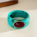 Detailed view of teal marbled acrylic bangle with large red oval gemstone insert - Irregular Geometric Style / Cyan And Wine Red