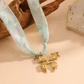 Detailed view of elegant golden butterfly pendant attached to a mint green silk ribbon - Bow Style (K806) / Gold with Light Green Scarf