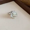 Nahaufnahme eines Silberrings mit einer weißen muschelförmigen Blume und Kristallakzenten - Ring / Silber-Weiß