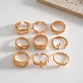 Set of vintage gold-tone rings featuring leaf, antler, and geometric metal designs. - 9-Piece Set / Gold