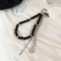 Close-up detail of black beaded keychain featuring silver chain, coin and cross charms - Coin Cross Black Bead Chain / Silver Black
