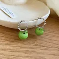 Primo piano di orecchini a mela verde con cerchi di perline argentate su un vassoio - Orecchini Perno Argento (HB5940) / Argento-Verde