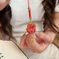 Primer plano de un amuleto de bolsa de bendición de gato de la suerte rojo con flores oro - Llavero / Red Lucky Bag